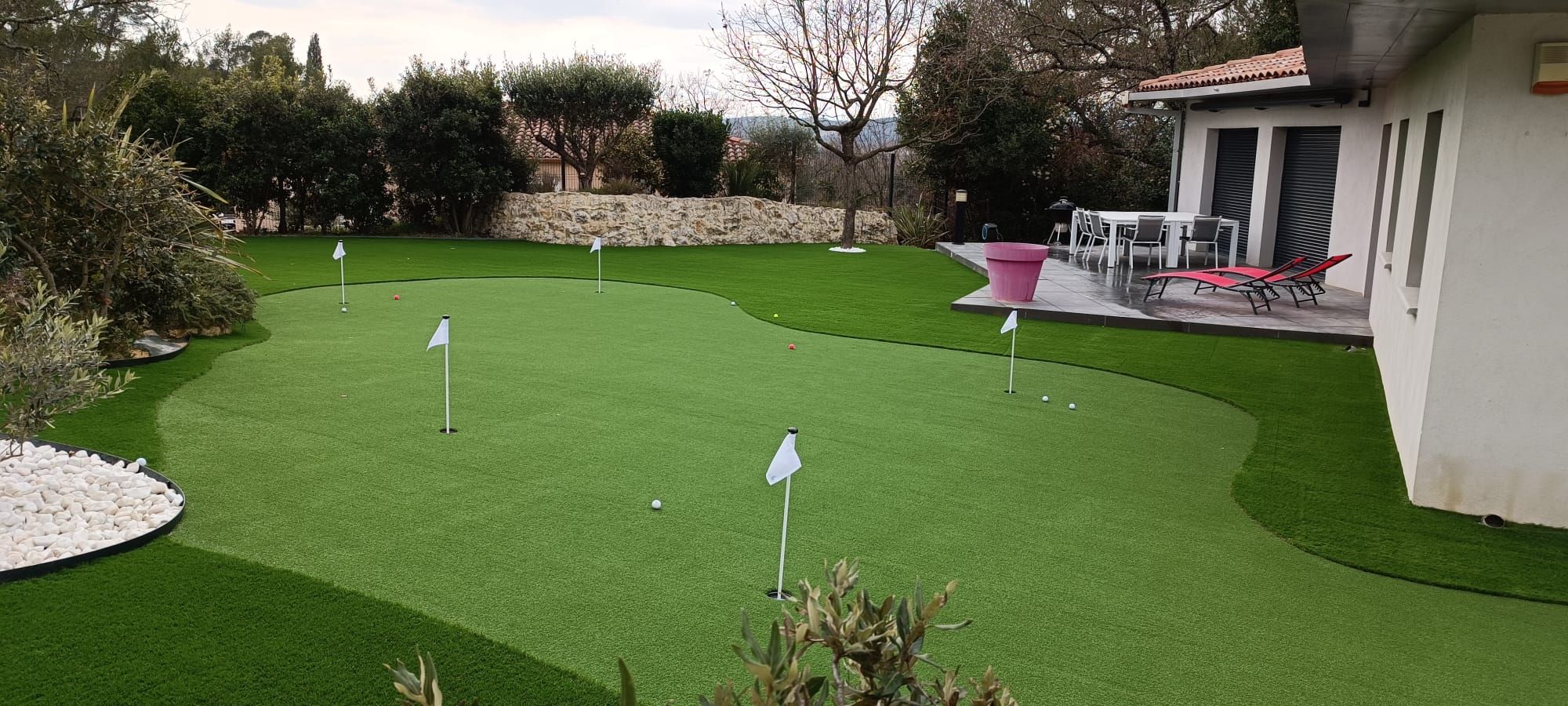 Putting green de golf en gazon synthétique dans un jardin, avec drapeaux